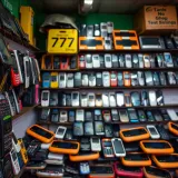 A vibrant Nigerian mobile phone market stall displaying a variety of used and refurbished phones on shelves